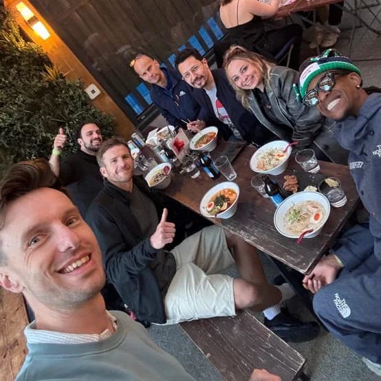 Greg taking a selfie with a group of friends around a dinner table