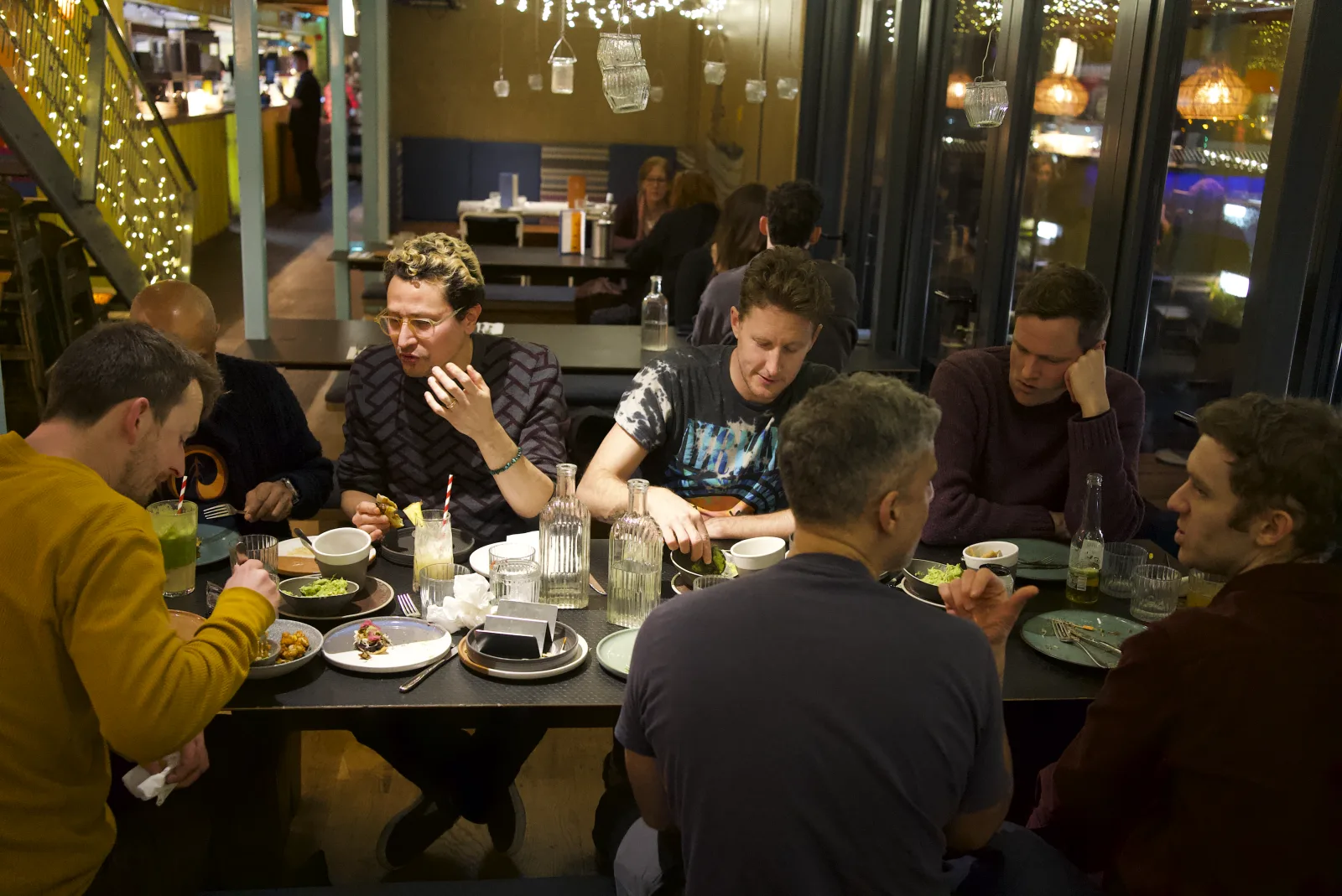 Men gathered around a table at an evening social meet-up in London