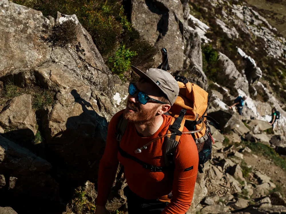 A hiker scrambling up rock with a full pack