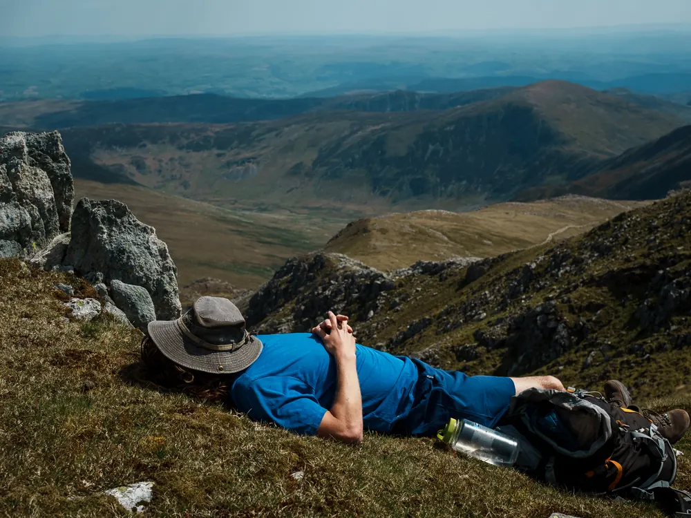 A man resting on the ridge above the valley on the way down