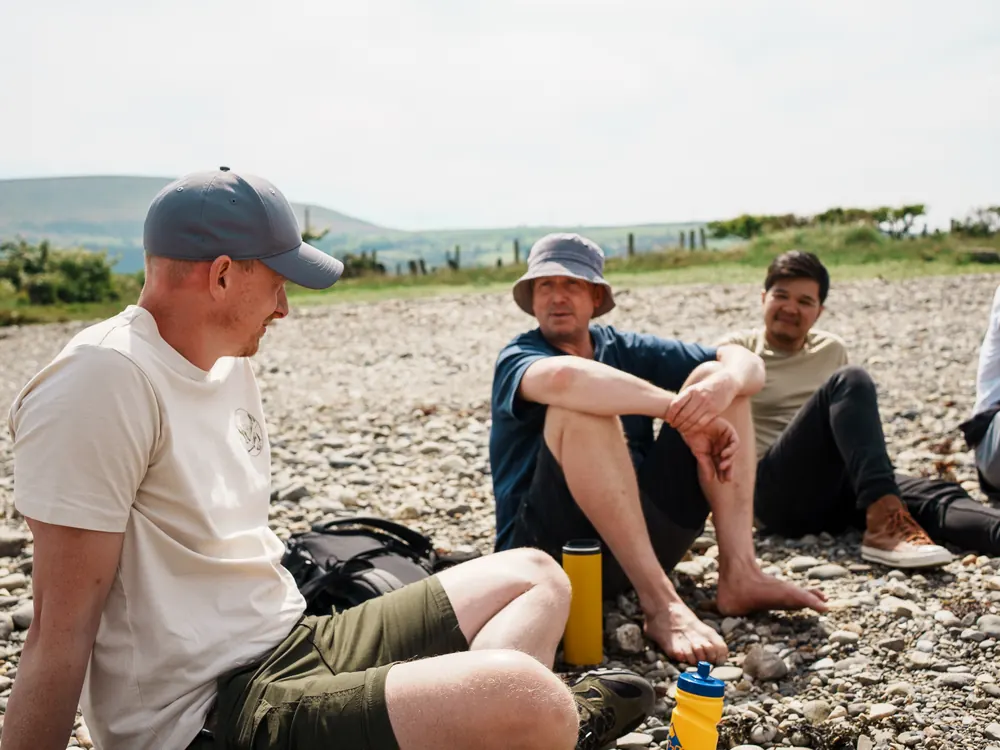 Men sitting by the lake talking in the sun, packs down