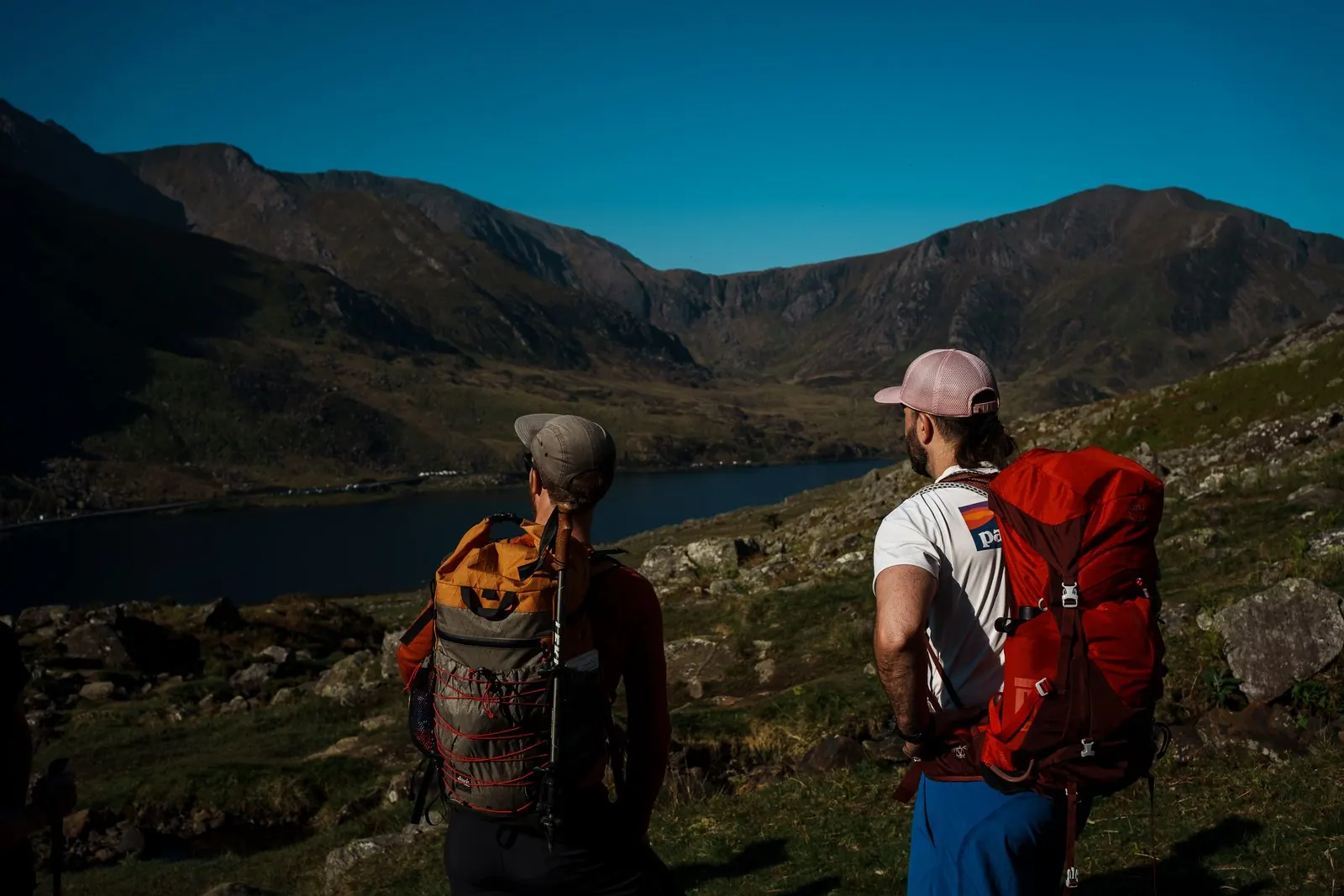 Two hikers looking out over a lake and ridges