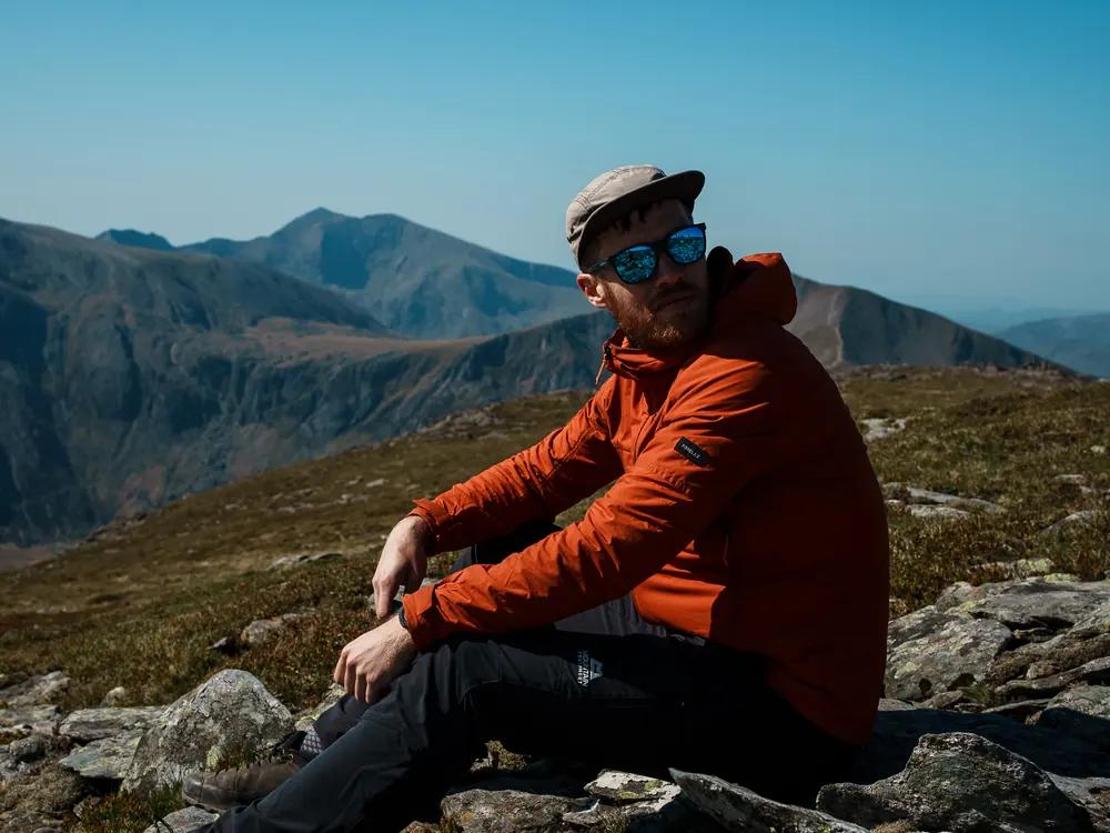 A man sitting alone on rocks looking out over the hills